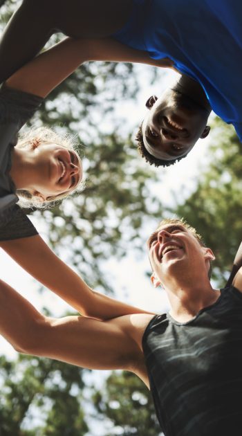 Fitness, happy or friends in nature for huddle for running exercise, training or outdoor workout together. People, low angle and healthy runners in park for motivation, support or sports teamwork.